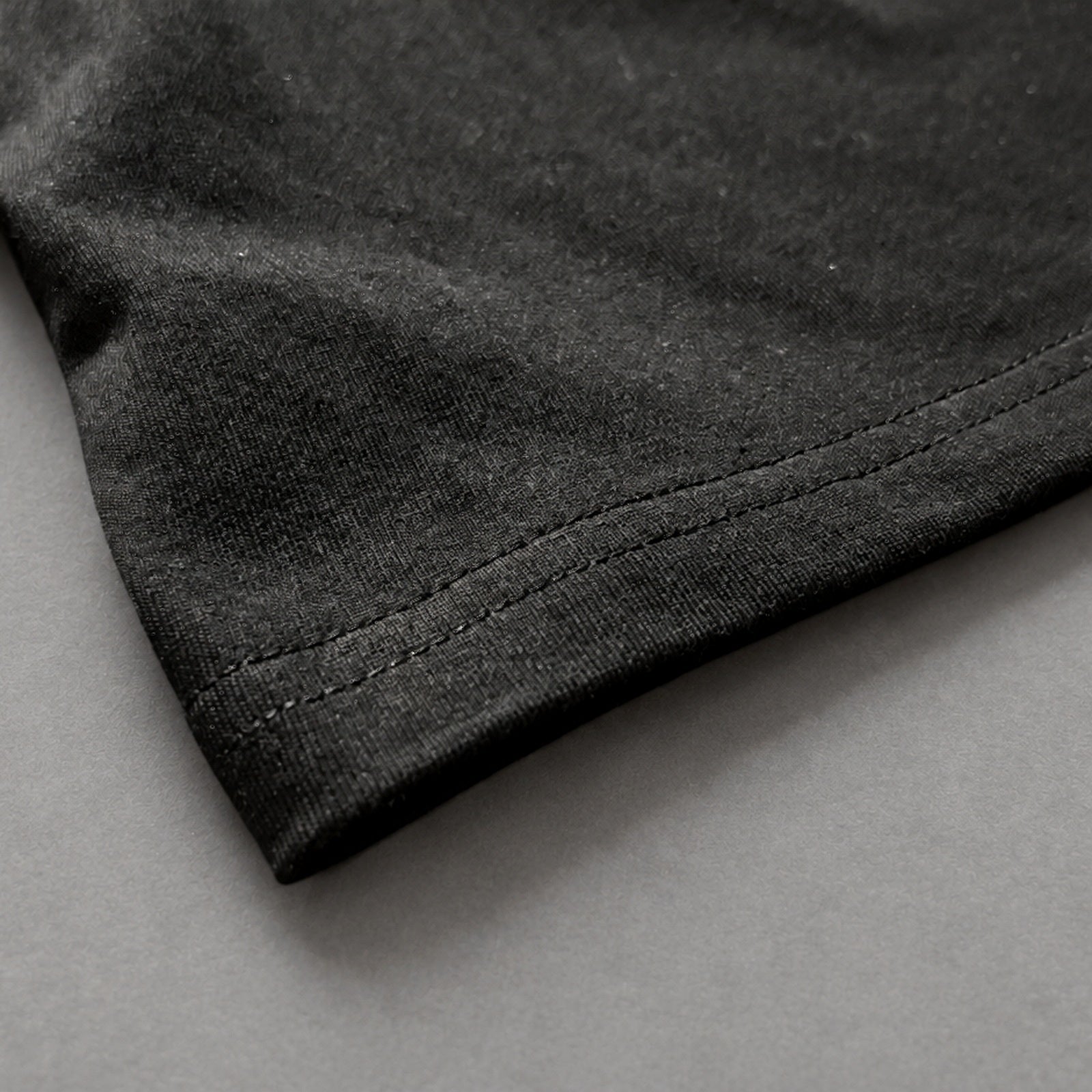 Black SJ Goods Tee hem and stitching detail on neutral gray